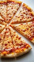 Cheese pizza cut into triangular slices on a white surface during bright daylight photo