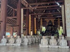Visitors observe numerous stone figures seated in a serene temple setting photo