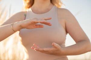 A womans hand gracefully holds a meditation pose, adorned with beads, as soft light enhances the serene and spiritual atmosphere. photo