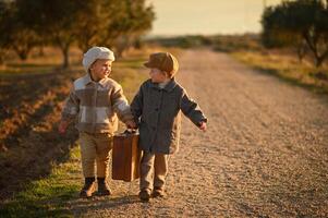 Dressed in old-fashioned outfits, the boys sit on a suitcase by the roadside, like travelers from the past. photo