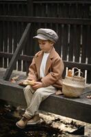 Dressed in old-fashioned clothes, a young boy carries a basket of fresh baguettes on a bridge, as if frozen in a timeless, nostalgic moment. photo