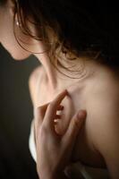 A delicate hand touches a womans skin, surrounded by a warm, muted beige color palette. photo