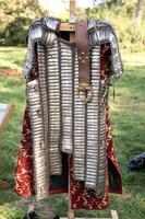 knight's iron armor chainmail made of plates. next to it is a belt with an iron buckle and a red shirt photo