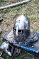 The knight's iron armor lies on the ground. The shield, chain mail, iron gauntlets, weapons of war, and helmet lie on the ground. photo