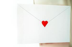 craft envelope made of white paper with a small cute heart. the envelope is located on the background of the interior. horizontal photo