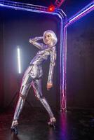 Blonde as cyber robot. Girl in shining silver armor in neon. Blonde with fantastic makeup and image in dark key and colored light, posing in cyberspace. She stands in a glowing cube photo