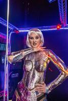 blonde as cyber robot. Girl in shining silver armor in neon. Blonde with fantastic make-up and image in dark key and color light, posing in cyberspace. screens and lightnings glow around photo