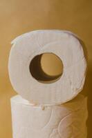 Close-up of stacked toilet paper rolls on a beige background in soft lighting. High quality photo