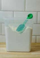 Flour in clear container with green scoop. in kitchen with white titles . High quality photo