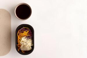 Grab-and-go container with a fresh Asian salad featuring cabbage, carrots, sesame, and teriyaki sauce. A vibrant, healthy, and delicious meal perfect for a quick and nutritious bite. . photo