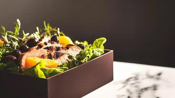 A fresh grab-and-go salad in a cardboard box, featuring grilled chicken, lettuce, olives, and lemon dressing. A vibrant and healthy meal with bright colors and appetizing textures. . photo