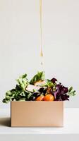 Fresh grab-and-go salad in a cardboard box with crisp lettuce, grilled chicken, black olives, and golden lemon dressing dripping from above. A healthy takeaway meal. . photo