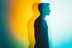 Silhouette of a person with dual-tone shadows in blue and yellow light, symbolizing mental health and self-reflection. A conceptual artistic portrait with contrast and depth. . photo