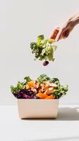 Grab-and-go salad in a cardboard box with fresh lettuce, grilled chicken, vibrant vegetables, and a levitating olive. Dynamic and playful composition with bright lighting. . photo