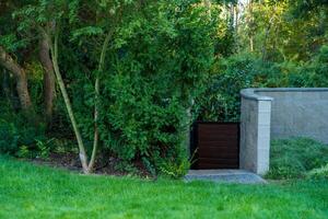 Lush garden gate surrounded by greenery and stone wall, calm atmosphere photo
