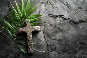 Palm Sunday. Stone cross with palm leaf on gray stone background with copy space. Religion, faith, Christianity concept photo
