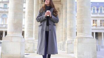 Parisian Woman in Grey Coat Strolling with Coffee at Royal Palace Columns video