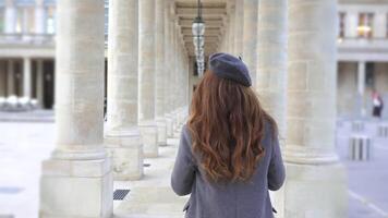 Girl in Gray Coat Walking with Coffee Between Columns in Paris video