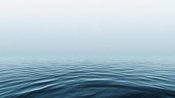 A serene, aquamarine expanse of the ocean, stretching to the horizon beneath a misty sky. The gentle waves create a tranquil seascape. photo