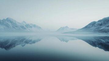 Serene expanse of water mirroring snow-capped mountains under a hazy sky, creating a tranquil scene. The scene is quiet and peaceful. photo