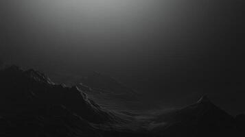 Mysterious, moody landscape of stark, dark mountain range under a gradient of deep shadows and a subtle glow from the sky above. photo