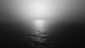 Monochromatic seascape with a bright spot of light reflecting off the water, creating an ethereal and calming atmosphere. photo