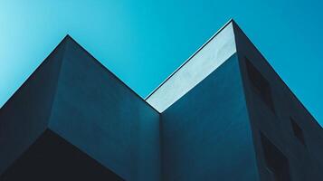 Modern architecture against a clear blue sky, emphasizing sharp geometric shapes and contrasting light and shadow, creating a minimalist aesthetic. photo