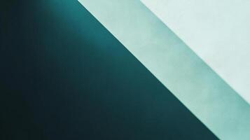 An abstract wall featuring a stark diagonal line separating a dark, cool shadow from a light, slightly warmer painted surface. photo