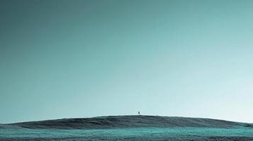 Solitary figure stands atop a grassy hill under a vast, serene sky. A moment of quiet reflection in a wide, open space. Simplicity at its finest. photo