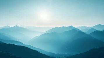 Layered mountain range disappearing in the distance, rendered in tones of blue, with the sun filtering through the haze. photo