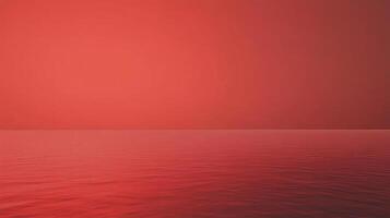 A monochromatic sunset illuminates a still ocean with a smooth gradient of intense red light, creating a serene and surreal scene. photo