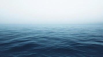 A tranquil ocean scene with gentle waves stretching to the horizon under a hazy, overcast sky, creating a peaceful, melancholic atmosphere. photo