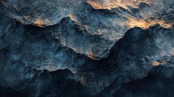 Aerial view of dark ocean waves, illuminated by golden sunlight, creating dramatic patterns and textures, showcasing nature's power. photo
