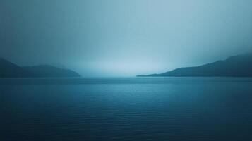A serene seascape on a hazy day, with gentle ripples across the water, distant hills rising from the horizon in a tranquil, misty atmosphere. photo