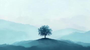 A solitary tree stands atop a hill against a backdrop of soft, misty mountains, evoking a sense of peace and solitude. photo