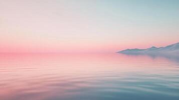 Serene seascape featuring a calm ocean reflecting a pastel sky, with distant snow-capped mountains adding to the tranquil atmosphere. photo