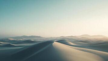 Serene desert landscape featuring rolling sand dunes under a soft, hazy sky with distant mountains on the horizon in muted colors. photo