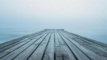 Tranquil pier extends to the horizon, where the pale blue water merges seamlessly into the fog filled sky, inviting a sense of serenity. photo