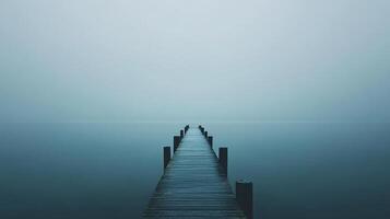 A wooden pier stretches into a misty horizon, creating a tranquil scene, inviting contemplation and a sense of serenity. Beautiful and peaceful. photo