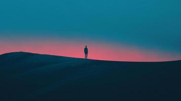 Solitary figure stands atop a dark hill against a vibrant gradient of pink and blue sky. The image evokes introspection and isolation. photo