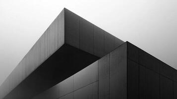 Monochromatic building corner with sharp lines, a modern concrete aesthetic, and structural intersection under a grey sky. Architectural geometry. photo