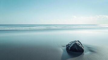 Tranquil beach scene with a smooth wet sandy shore and a solitary rock in the foreground under a clear sky. Serene seaside landscape. photo