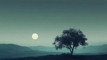 A solitary tree silhouetted against a pastel sky and mountain range, illuminated by the full moon, in the middle of an open field. photo