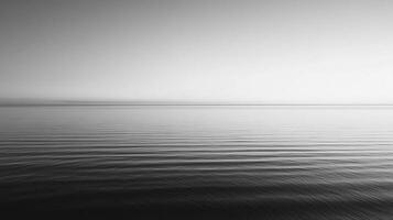 Monochromatic seascape displaying the soft gradient of a calming sea meeting the horizon under a serene, light-filled sky. photo