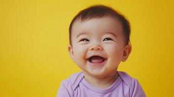 A joyous baby with wide, bright eyes beams with an open-mouthed smile. The baby's cheerful expression conveys pure delight and innocence. photo