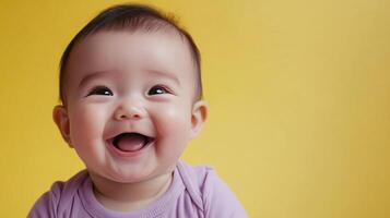 A captivating baby portrait with a wide, happy grin, set against a bright yellow backdrop. The focus is on the child's expressive face. photo