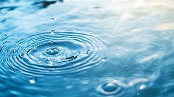 Water droplets creating concentric ripples on a calm surface, capturing the beauty of nature's patterns in shades of blue and white. photo