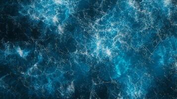 Aerial view of frothy ocean water, showcasing patterns and textures. The deep blue hues create a visually striking abstract. photo