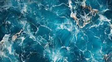 A mesmerizing aerial view captures the interplay of deep turquoise water, foamy crests, and swirling patterns in the vast ocean surface. photo