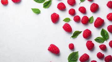 Fresh raspberries and green leaves scattered across a clean white surface, creating a vibrant and natural composition. Background, close-up. photo